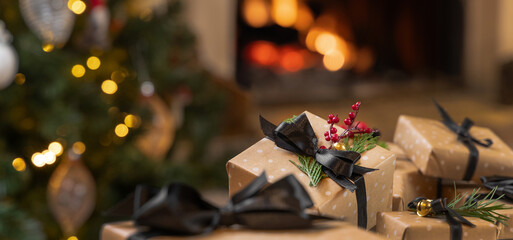 Christmas gifts with black bows on background of burning fireplace and christmas tree