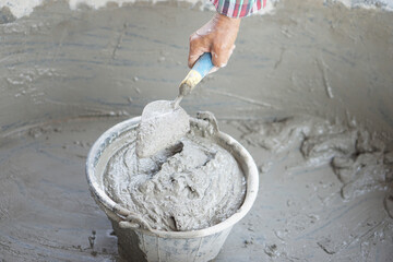 Close up worker hand hold a trowel to mix wet cement in bucket. Concept. Construction  job. Process...