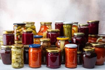 Preserving vegetables for the winter, a lot of glass jars with canned vegetables and adjika, jam and vegetable salads, pickled or fermented vegetables, copy space