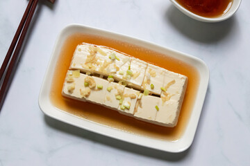 Vegan silken tofu is served hot or cold with a savory soy sauce flavored with green onions, grated ginger and sesame oil.
