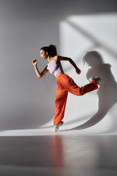 A stylish African American woman in trendy attire strikes a dynamic pose against a grey backdrop.