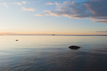 Fototapeta premium Seascape in the Baltic Sea during a calm summer evening after sunset, a cargo ship stands on the horizon.