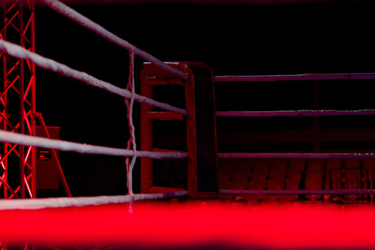 Empty boxing ring with red ropes for match in the stadium arena. Creative artwork decoration. Foggy background with light. Selective focus