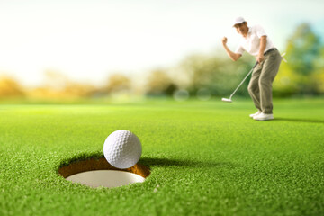 Golf ball drop into the hole after golfer putting.