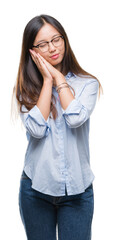 Young asian business woman wearing glasses over isolated background sleeping tired dreaming and posing with hands together while smiling with closed eyes.