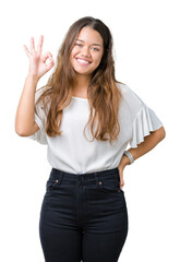 Obraz premium Young beautiful brunette business woman over isolated background smiling positive doing ok sign with hand and fingers. Successful expression.