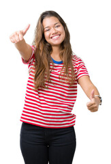 Young beautiful brunette woman wearing stripes t-shirt over isolated background approving doing positive gesture with hand, thumbs up smiling and happy for success. Looking at the camera.