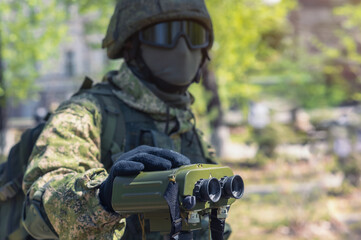 A soldier in camouflage gear demonstrates an army rangefinder-angle meter. Military technology....