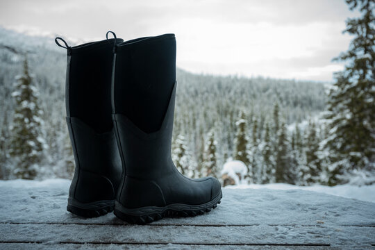 Pair of black boots on snow covered bench