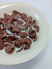 Coco Crunch Cereal Drowned in Milk in a Small Cream Bowl on White Background: Enjoy a Delicious Breakfast Indulgence with Crunchy Cereal Submerged in Creamy Milk
