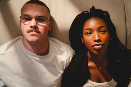 Directly above shot of young couple looking away while lying down on sofa at home
