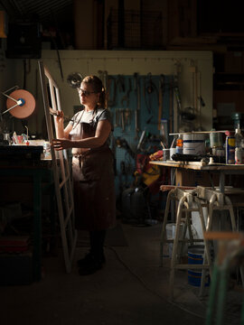Woman painting window frame at workshop
