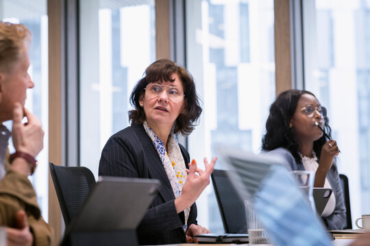 Mature businesswoman looking at colleagues during meeting in office