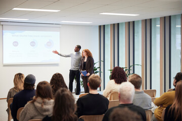 Multiracial coworkers giving presentation to colleagues in office