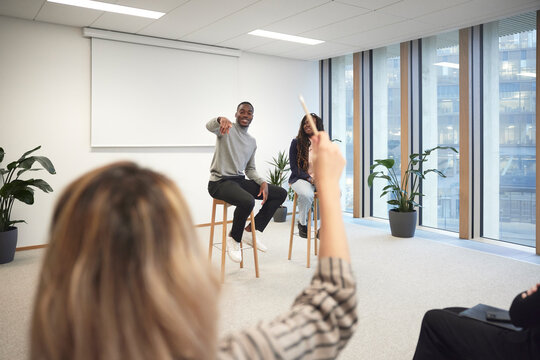 Businessman pointing at colleague to ask question during meeting in office