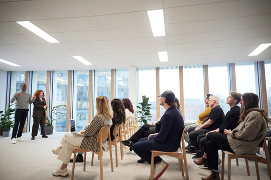 Participants listening to multiracial coworkers during meeting in office