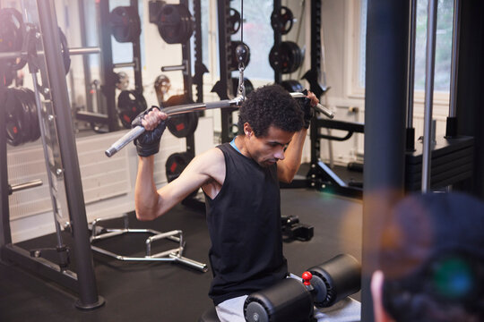 Young man doing lateral pull-down weightlifting at gym