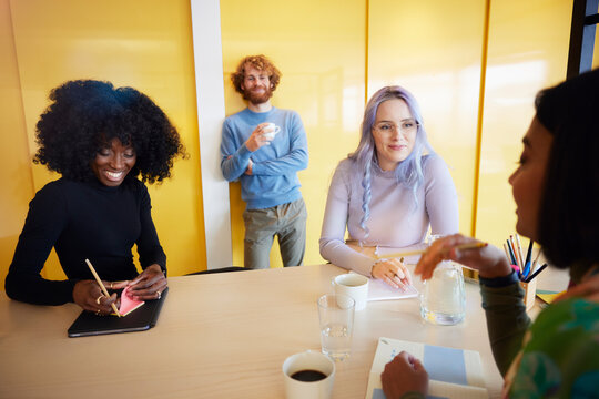 Coworkers listening to businesswoman during meeting in office
