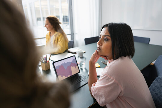 Serious businesswoman looking away while sitting over table in office
