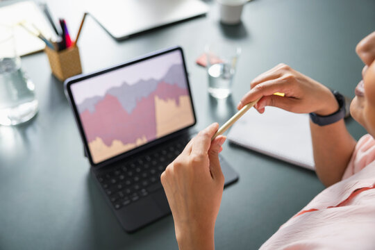 Midsection of businesswoman holding pencil while analyzing graph on digital tablet in office