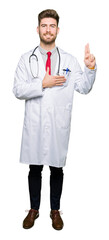 Young handsome doctor man wearing medical coat Swearing with hand on chest and fingers, making a...