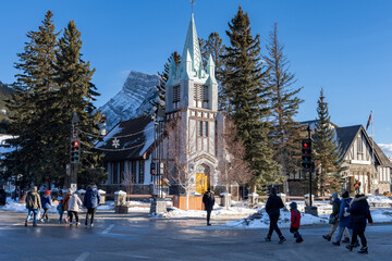Banff, Alberta, Canada - January 23 2022 : Downtown Banff Avenue in winter. Pedestrians are crossing the road during covid-19 pandemic period.