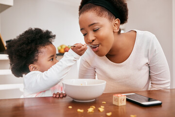 Black family, baby and feeding mother in home, food and meal for nutrition at breakfast in kitchen. Mommy, daughter and helping mom or support on weekend, love and child for morning bonding together
