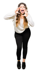 Young beautiful woman wearing white sweater Shouting angry out loud with hands over mouth