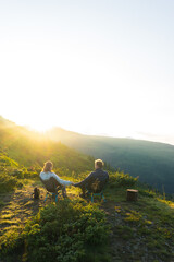 a couple, a man and a woman, sits in a tourist chair on a hill overlooking a mountain range, on the background of mountains, tourism, hiking, time together, family, relationships, nature of the Carpat