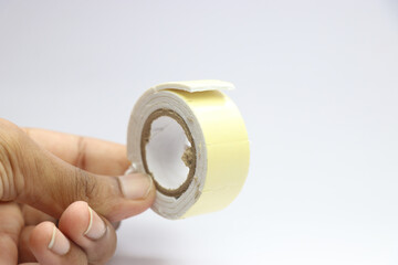 Two sided tape or also known as double sided adhesive held in hand on white background