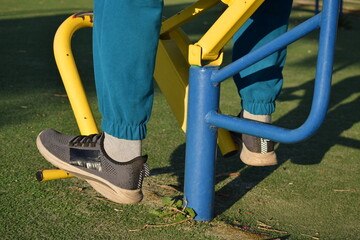 A young man in athletic wear performs morning workout routine at an outdoor gym. He trains...