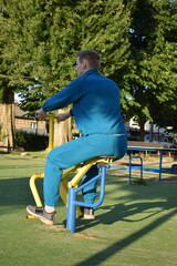 A young man in athletic wear performs morning workout routine at an outdoor gym. He trains...