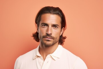 Fototapeta premium Portrait of a tender man in his 30s donning a trendy cropped top isolated in pastel orange background