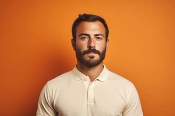 Fototapeta premium Portrait of a blissful man in his 30s donning a classy polo shirt on pastel orange background
