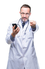 Middle age senior hoary doctor man texting using smartphone over isolated background pointing with finger to the camera and to you, hand sign, positive and confident gesture from the front