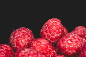 Close up shot of fresh ripe red raspberries on the black background
