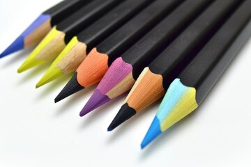 Naklejka premium Close-up of vibrant colored pencils in a row, showcasing a variety of colors with black bodies, ideal for art and design projects.