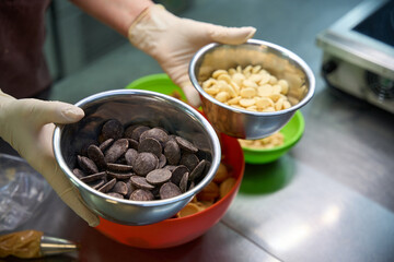 Confectioner holding two bowls with white and brown chocolate chips