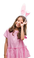 Brunette hispanic girl wearing easter rabbit ears with happy face smiling doing ok sign with hand...