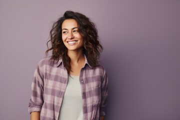 Fototapeta premium Portrait of a happy woman in her 30s wearing a comfy flannel shirt in front of pastel gray background