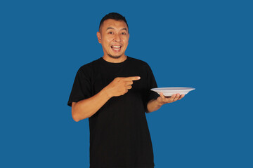 Attractive and confident Asian man pointing to right side of empty plate
