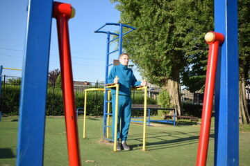 A young man in athletic wear performs morning workout routine at an outdoor gym. He trains...