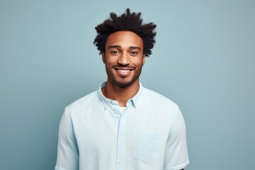 Fototapeta premium Portrait of a satisfied afro-american man in his 20s wearing a simple cotton shirt in front of pastel gray background
