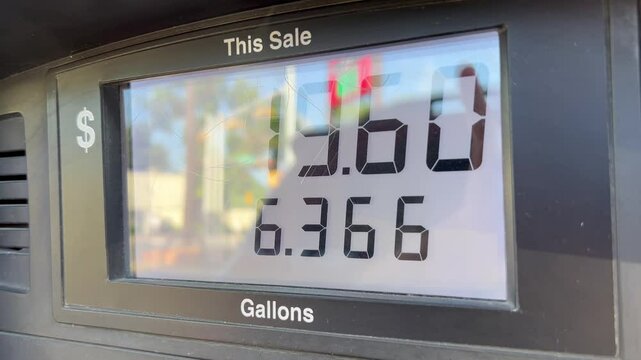 Gas price meter display rising with cars in reflection on 7/4/2024