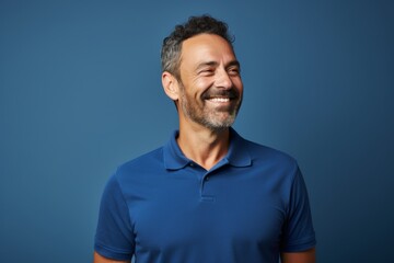 Portrait of a satisfied man in his 40s wearing a sporty polo shirt isolated in soft blue background