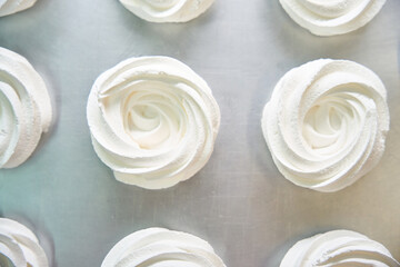 Top view to white crispy and airy merengue drying out on the tray
