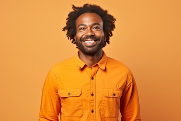 Fototapeta premium Portrait of a jovial afro-american man in his 30s sporting a breathable hiking shirt isolated in soft orange background