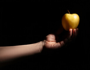 golden delicious apple in hand on black background