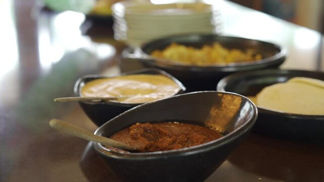Close up panning of black carrots with curry sauce and other sauces in blur background, ready to serve