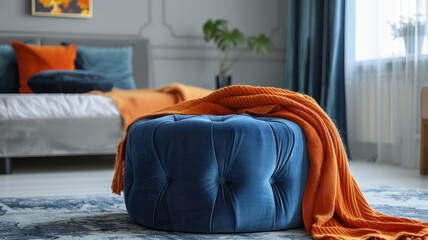 Blue ottoman with orange blanket in a modern bedroom.